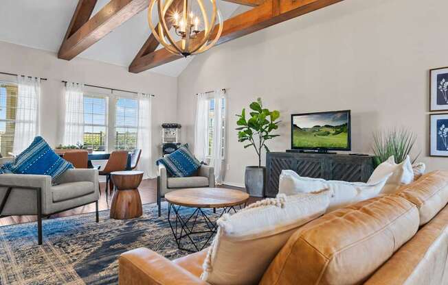 A living room with a brown couch, a grey armchair, a wooden coffee table, and a television.