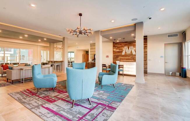 A spacious living room with a chandelier, blue chairs, and a patterned rug.
