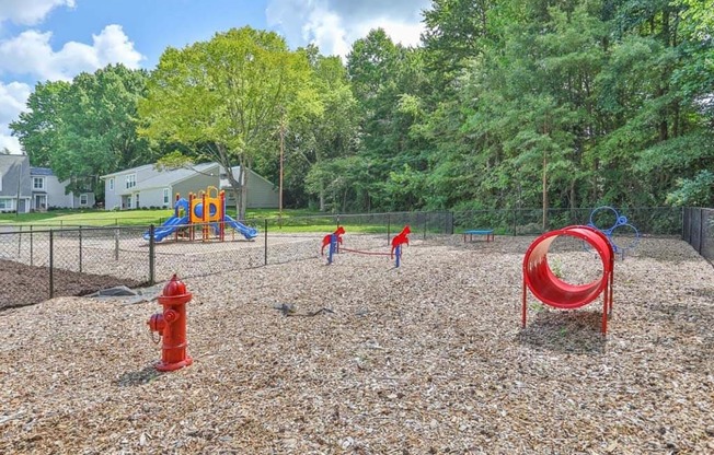 a playground with a fire hydrant in the foreground and trees in the background