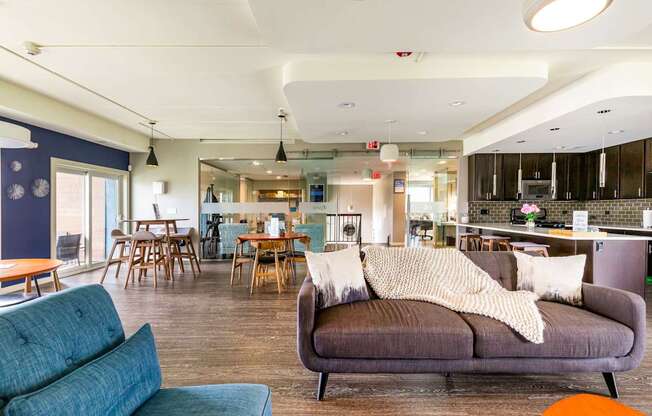 A living room with a grey couch and a dining area in the background.