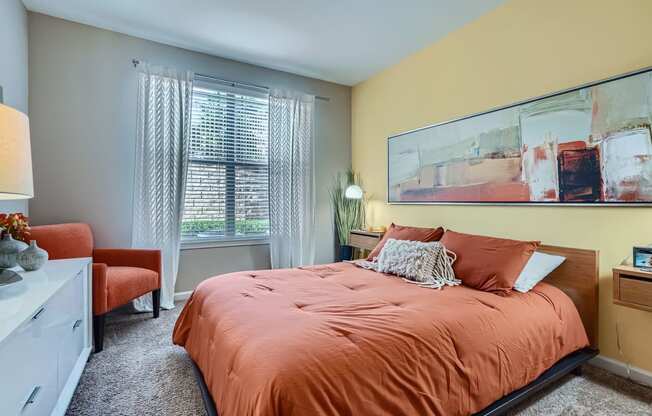 a bedroom with an orange bed and a painting on the wall