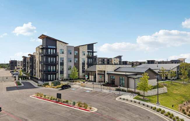 A large, modern apartment complex with a parking lot in front.