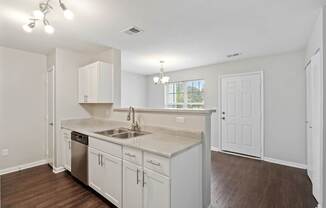 A kitchen with white cabinets and a wooden floor.