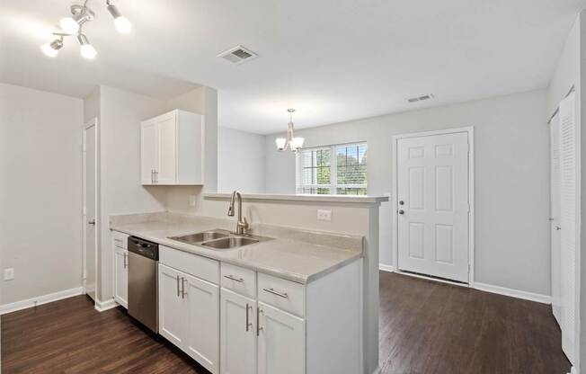 A kitchen with white cabinets and a wooden floor.