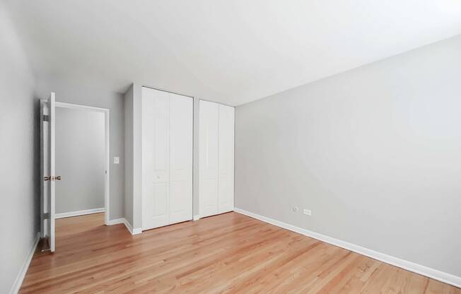 a bedroom with hardwood floors and white walls