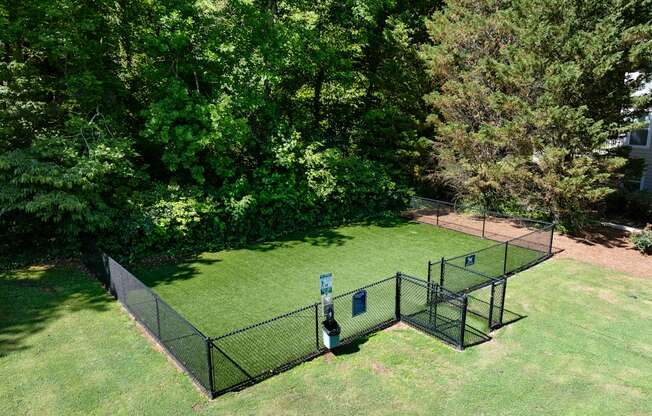 A black fenced area with a blue sign in the middle of a grassy field.