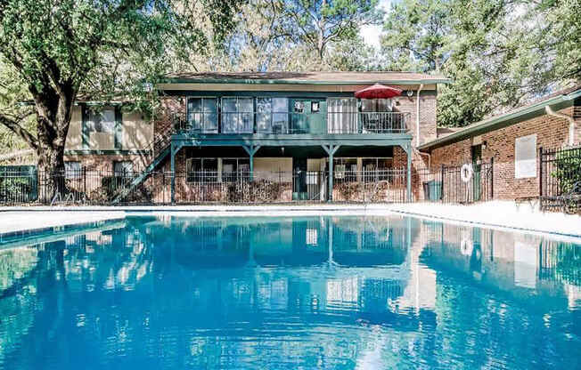 A swimming pool in front of a house with a balcony.