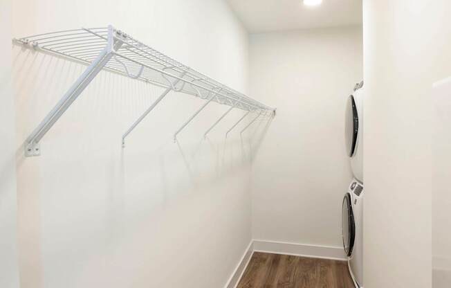 A white laundry room with a clothes dryer and a clothes rack.