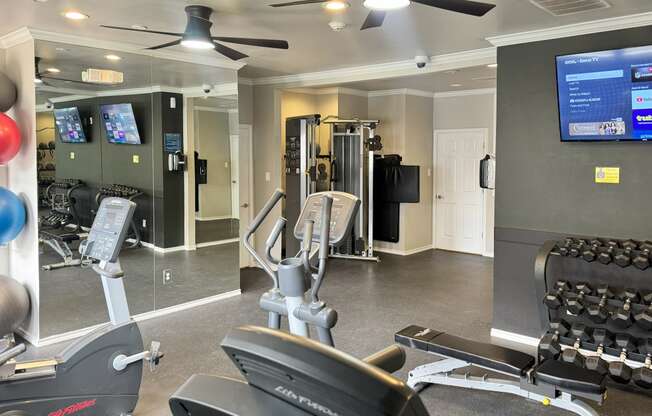 a gym with cardio equipment and a tv in a building