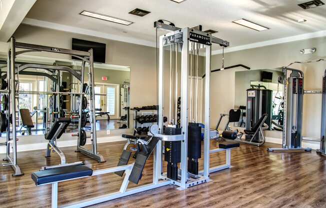 a gym with cardio equipment and weights on a wooden floor