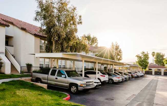 A parking lot with cars parked in front of a building with a tree in the background.
