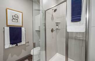 a bathroom with a glass shower stall and blue towels