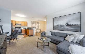 a living room with a couch and a coffee table in front of a kitchen