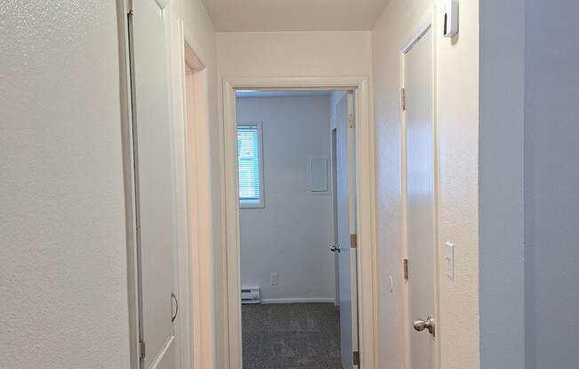 a hallway with a carpeted floor and a window at the end of the hallway