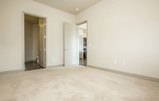 a living room with a carpeted floor and a door to a bedroom