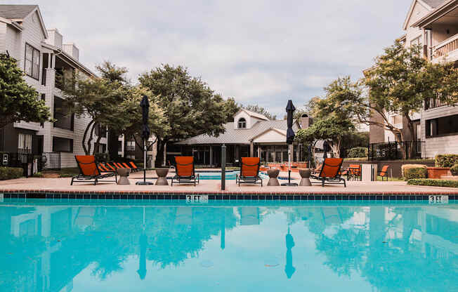 the residence apartment pool with chairs and buildings in the background