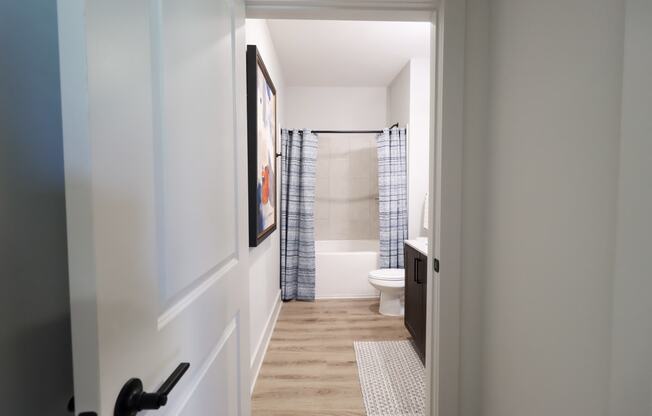 a hallway with a door to a bathroom with a shower and a toilet