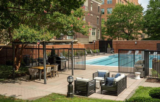 a swimming pool with chairs and tables in a courtyard