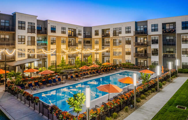 an apartment building with a swimming pool at dusk