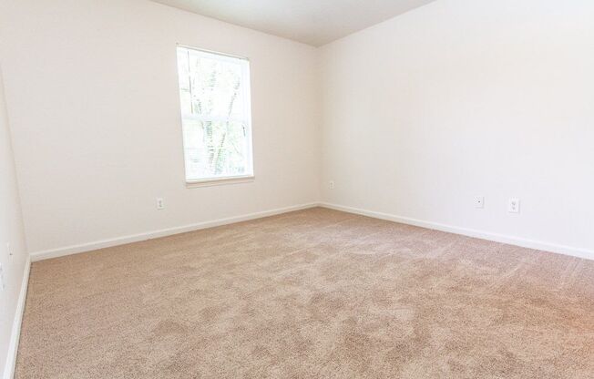 An empty bedroom with white walls, a window, and carpet at Maple Tree Apartments in LaPorte, IN