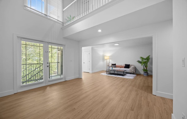 A spacious room with wooden floors and a staircase leading to the upper level.