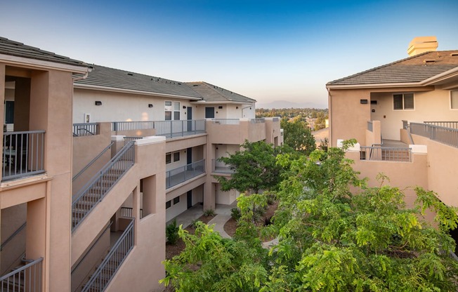Apartment complex with balconies and trees in the foreground.