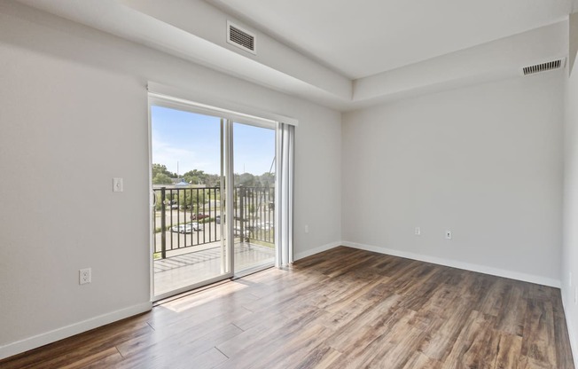 an empty living room with a sliding glass door to a balcony