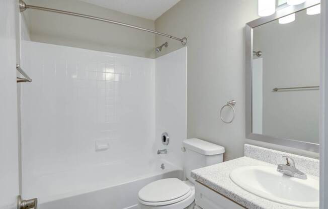 A white bathroom with a toilet, sink, and shower.