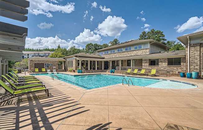 A swimming pool surrounded by lounge chairs and a building in the background.