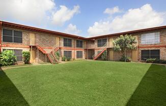 a large brick building with green grass in front of a house