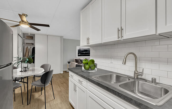 a kitchen with white cabinets and a sink and a table with chairs