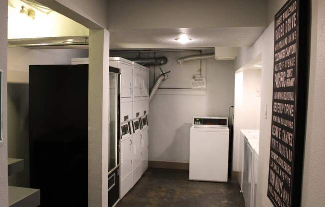 Pasadena Brookmore apartments on site laundry room with eight washers and dryers and a black vending machine on concrete floors