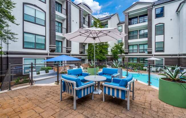 a patio with chairs and an umbrella next to a swimming pool