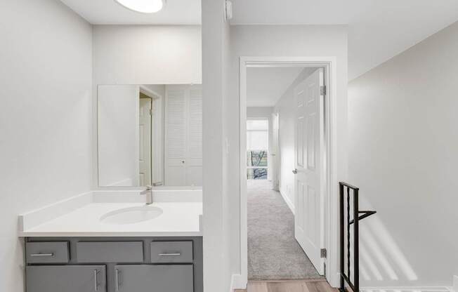 A bathroom with a sink, mirror, and cabinets.