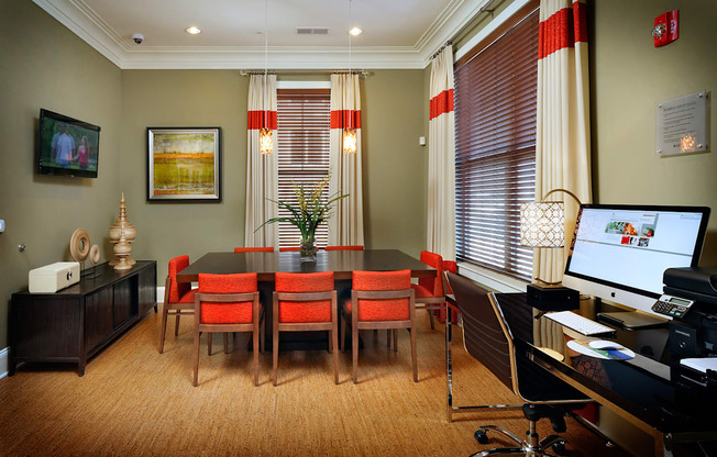 A conference room with a long table and chairs, a computer desk, and a printer.