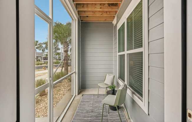 a covered porch with two chairs and sliding glass doors at Palm Grove in Ellenton, FL