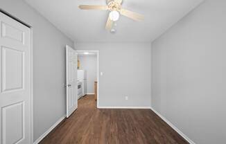 a spacious living room with white walls and a ceiling fan