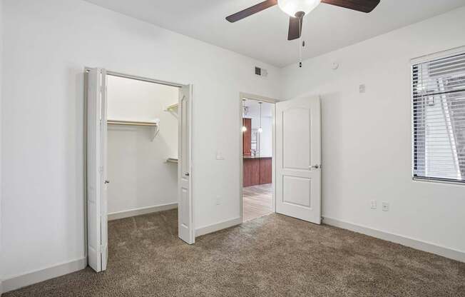 A room with a ceiling fan and carpeted floor.