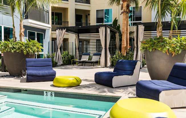 A poolside lounge area with blue and yellow cushions.