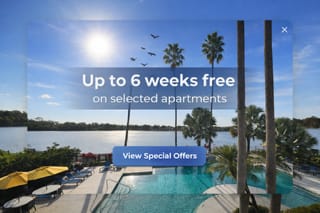 A sunny day at a poolside with a sign offering free weeks on selected apartments.