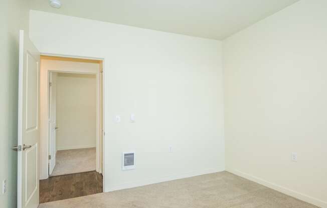 an empty room with white walls and a door to a hallway