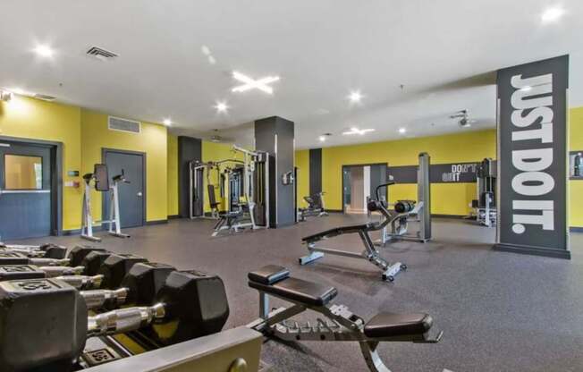 A gym with a variety of equipment including dumbbells and weight machines.