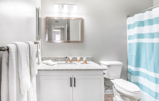 a white bathroom with a blue and white shower curtain