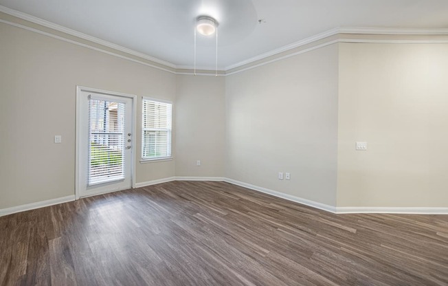 an empty living room with wood flooring and a window