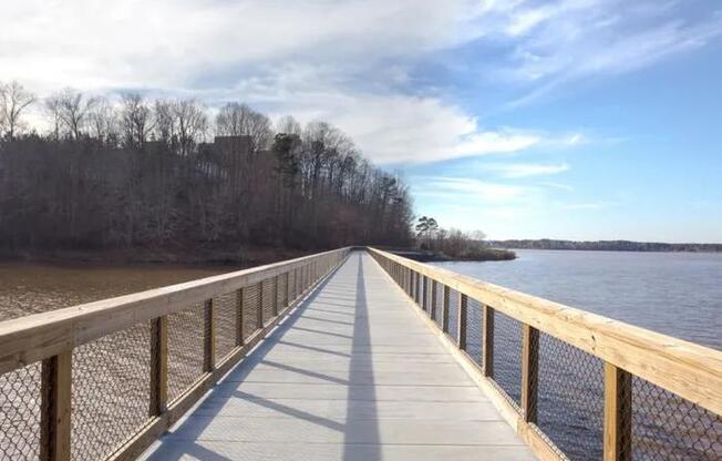 A wooden boardwalk extends into a body of water with trees on the side.