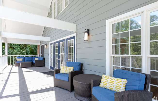 a covered porch with blue chairs and yellow pillows