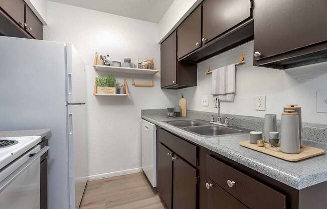 A small kitchen with a white refrigerator and brown cabinets.