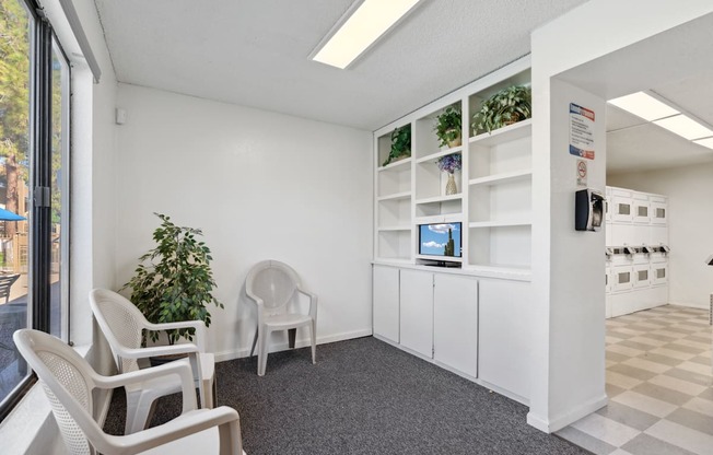 A room with white chairs and a white cabinet with a computer on it.