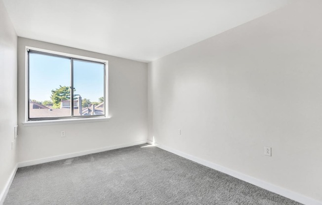 an empty room with a window and carpet