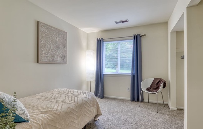 a bedroom with a bed and a chair and a window